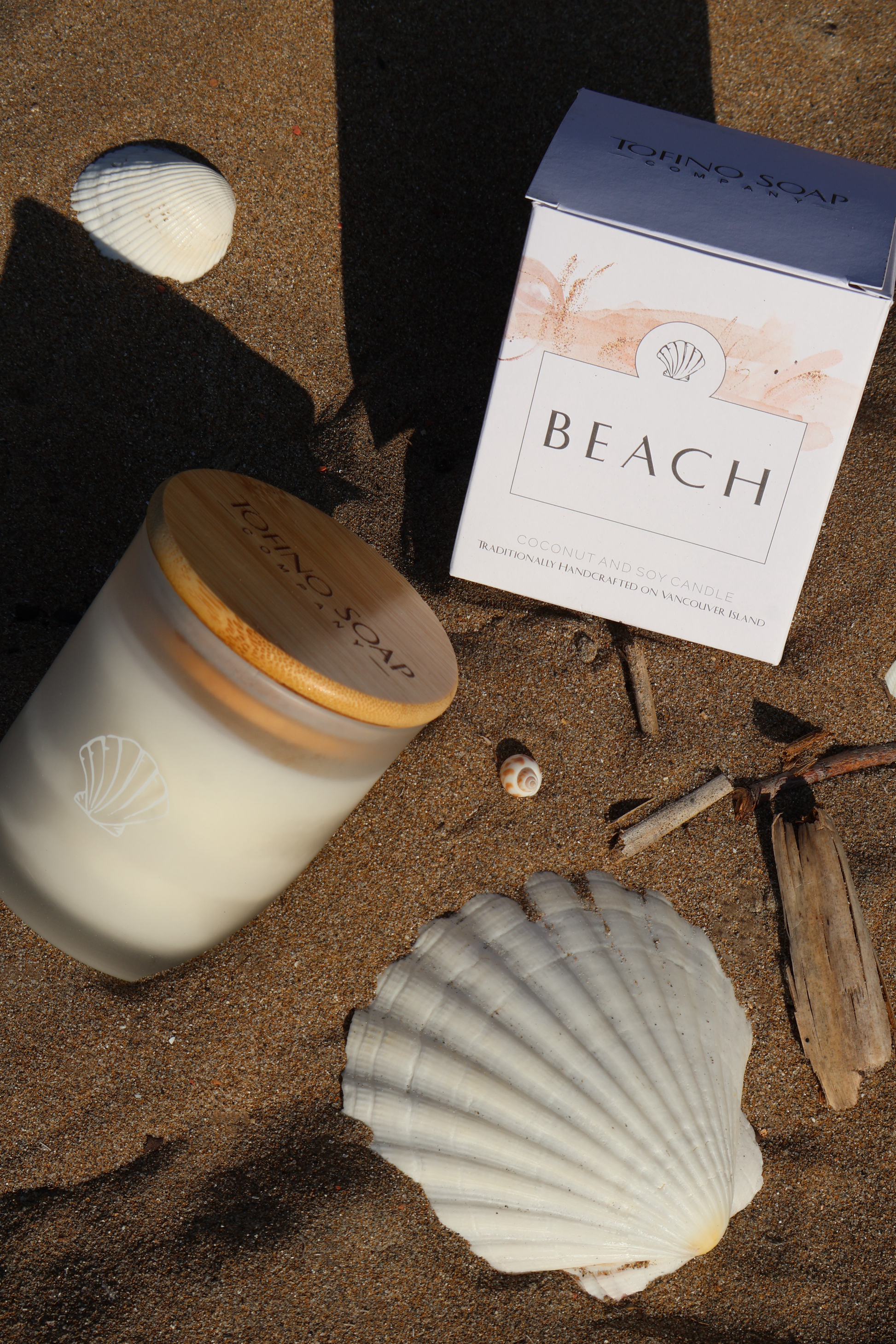 Candle, box labeled 'Beach', and seashell on sand