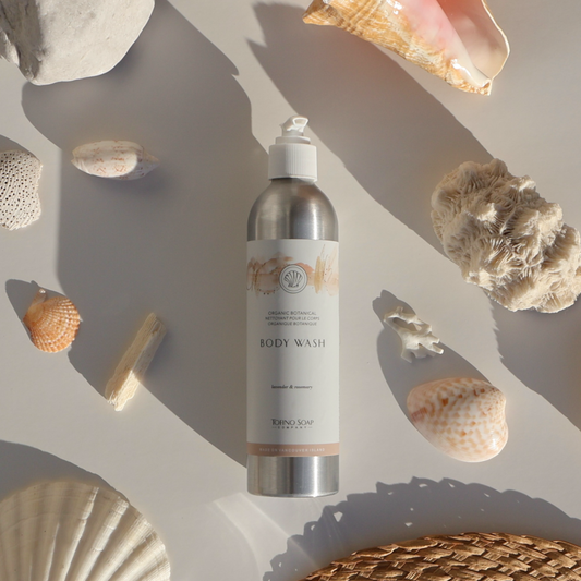 Body wash bottle surrounded by seashells and natural stones on a neutral background