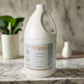 Large white bottle of shampoo on a light surface with a neutral background
