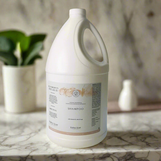 Large white bottle of shampoo on a light surface with a neutral background