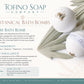 Tofino Soap Company Botanical Bath Bombs 'Surf Bath Bomb' packaging card with two round bath bombs wrapped in white paper, shown on a light beige background with botanical illustrations and product details.