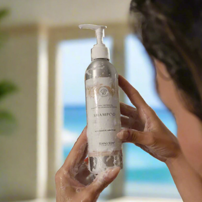Person holding a bottle of shampoo with a blurred background